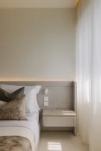 Modern minimalist bedroom with a wooden floating nightstand and white bedding.