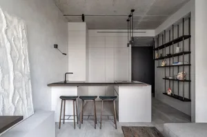Modern minimalist kitchen featuring concrete countertops and wooden stools.