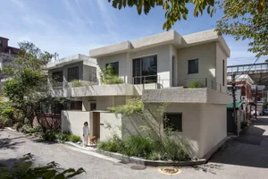A modern residential building with a concrete facade and greenery.