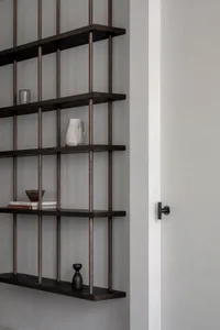 A modern shelf with dark wood and decorative items including a vase and books.