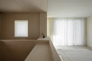 A minimalist bedroom with wooden walls, fabric curtains, and a simple bed setup.
