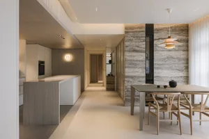 Modern residential kitchen and dining room with concrete and marble elements.