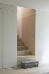 Modern minimalist staircase interior with wood stairs and white walls.