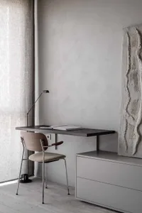 A minimalist home office space featuring wooden desk and concrete elements.