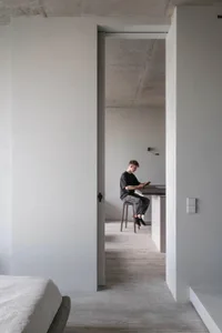 A minimalist residential space featuring industrial-style concrete, wood, and metal finishes.
