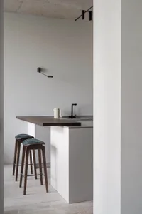 Modern kitchen featuring wooden stools, concrete countertop, and metal faucet.