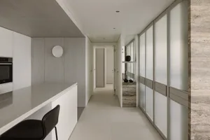 A modern minimalist kitchen featuring white materials, with an open layout and a sleek, minimalistic design.