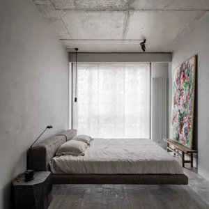 Modern minimalist bedroom with a textured concrete ceiling, large window with sheer curtains, and an abstract painting leanin