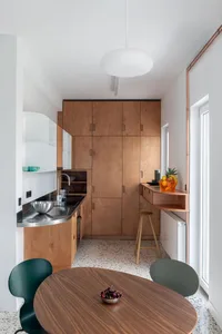 A minimalist kitchen featuring wooden cabinets, metallic countertops, and glass elements.