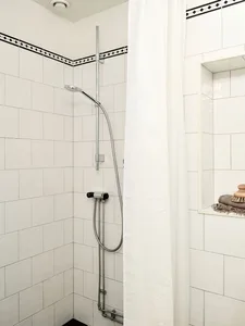 White-tiled minimalist bathroom shower area with a shower curtain and built-in niche.