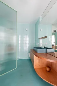 A modern bathroom with ceramic tiles, a wooden vanity, and a glass shower enclosure.