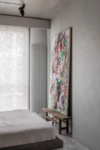 Modern bedroom with a fashionably styled interior, featuring an abstract painting leaning against the wall.