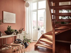 A modern interior design featuring a wooden staircase with plants and a textured wall.