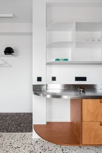 Modern kitchen with metallic countertops, wooden cabinets, and terrazzo flooring.