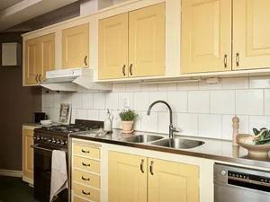 A modern kitchen featuring wooden furniture, stainless steel appliances, and a white subway tile backsplash.
