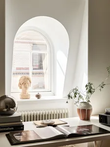 A minimalist desk space featuring a plant, ceramic vase, and books.
