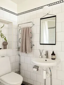 Minimalist bathroom with white tiled walls, white fixtures, and a gray towel hanging on a towel rack.