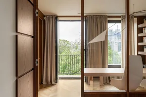 A modern dining room with contemporary design elements, featuring a wooden dining table and a view of the outdoors through a