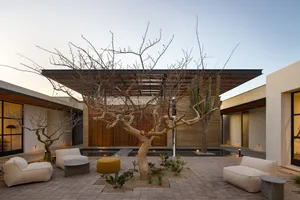 A modern garden lounge featuring concrete furniture, canvas seating, and matte lighting fixtures.