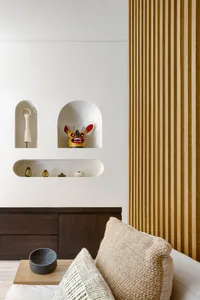 A modern living room with wooden shelving featuring decorative objects and a textured sofa.