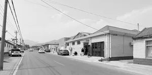 A street view image showing a road with cars, buildings, and electrical wires.