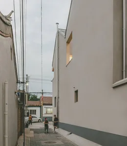 A narrow urban alleyway made of concrete with pedestrians and electrical wires.