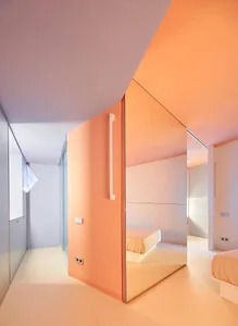 Modern minimalist bedroom featuring orange painted surfaces and large mirrors.