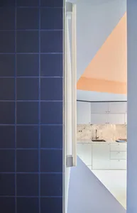 A minimalist kitchen featuring concrete walls and flooring, with a geometric design and white cabinets.
