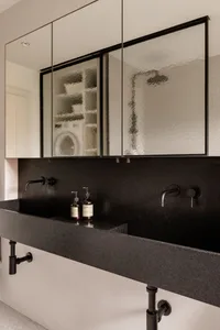 A modern bathroom interior featuring a black concrete countertop sink, dark tiles, and a minimalist design.