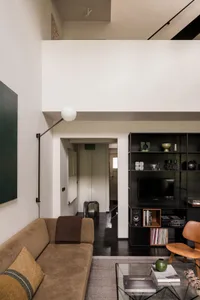 A modern living room featuring a brown fabric sofa, wooden chair, and glass coffee table.