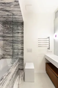 Modern bathroom with marble walls, white floor, and white toilet.