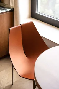 Brown leather chair with a sleek, minimalist design, placed near a window.