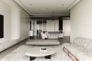 A modern minimalist living room with a sleek, white bench, a round white coffee table, a light grey sofa with red accents, an