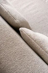 A minimalist sofa with a tweed textile upholstery, featuring a light, neutral color palette and a modern design.