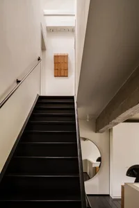 A sleek, modern staircase with black steps and a concrete floor.