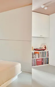 A minimalist bedroom with concrete flooring, white walls, and a pink ceiling.