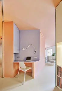 A modern home office featuring a desk with a laptop and lamp, surrounded by pastel-colored walls.