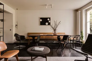 Modern minimalist living room featuring wooden furniture and a vase of twigs.