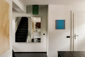 A modern interior design featuring concrete walls, black tiled flooring, and large mirrors.