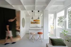 A modern, minimalist kitchen with white surfaces and an open-plan design.
