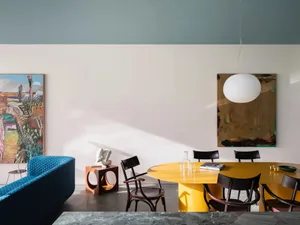 Modern interior design featuring a yellow metal dining table and black chairs.