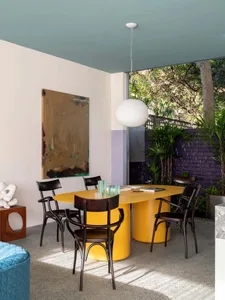 Modern, stylish dining room with a yellow metal dining table and black chairs.