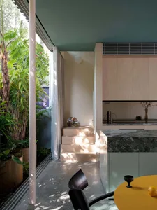 A modern living, dining, and kitchen area featuring concrete, marble, and wood materials.