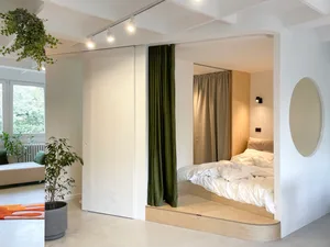 A modern minimalist bedroom with a platform bed, grey walls, and green curtains