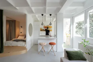 A modern open-concept apartment with a white color scheme and wooden accents.