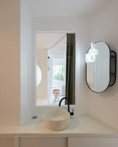 Modern residential bathroom with concrete sink and mirror, glass window, and green curtains.
