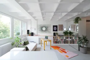 A modern living room with a white-painted ceiling and walls, featuring minimalistic furniture and a bright, open floor plan.