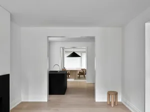 A modern minimalist kitchen with a wooden countertop and pendant light fixture.