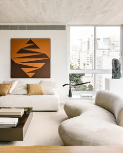 Modern, minimalist living room featuring a white fabric sofa, abstract art, and a view of the city through large windows.