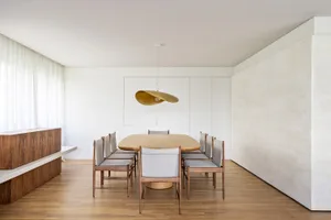 A modern dining room featuring a wooden table and chairs, with minimalist design and clean lines.